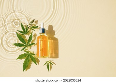 CBD-Öl in Tröpfchenflasche, Cannabisblätter, transparenter öliger Hintergrund
