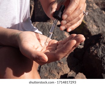 CBD Oil In Eye Dropper And Hands. Woman Using CBD Oil.