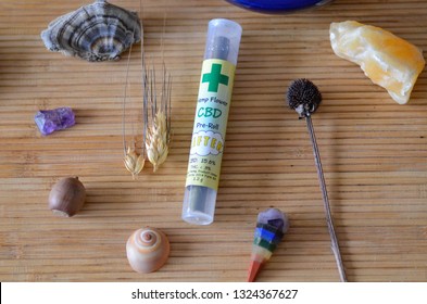 CBD Pre-Rolled Blunt, Hemp Flower, Unlit In Tube On Bamboo Mat, Surrounded By Healing Stones, Sage, Pendants 