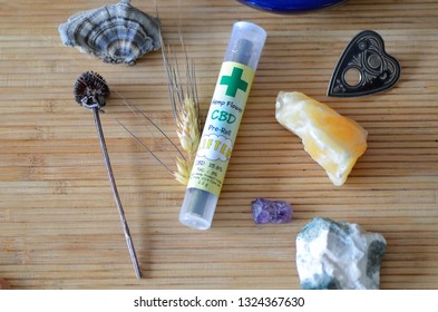 CBD Pre-Rolled Blunt, Hemp Flower, Unlit In Tube On Bamboo Mat, Surrounded By Healing Stones, Sage, Pendants 