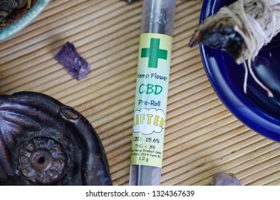 CBD Pre-Rolled Blunt, Hemp Flower, Unlit In Tube On Bamboo Mat, Surrounded By Healing Stones, Sage, Pendants 