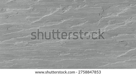 cClose-up of a grey split-face slate stone wall with a natural layered texture and horizontal sedimentary rock patterns.