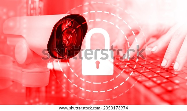 CCTV camera on red background. Hands on\
keyboard near camera. Data security video surveillance system.\
Cyber security system. Video surveillance software development\
metaphor. CCTV integration