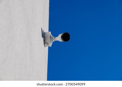 A CCTV camera is securely mounted on a wall, focused towards the open sky, ensuring constant monitoring and security for the surrounding area.