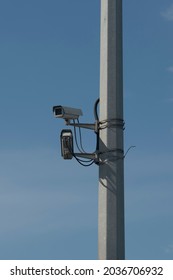 CCTV Cameras On A High Pillar At The Edge Of A Road Bridge. Video Surveillance Of Car Traffic On The Bridge Over The River.