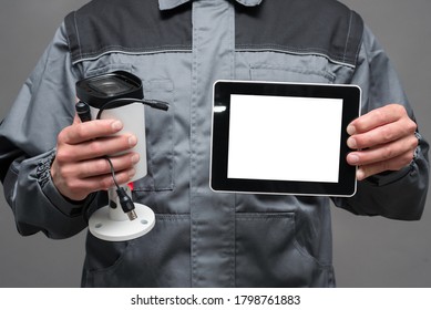 CCTV installation worker with a security camera and blank screen digital tablet close up.