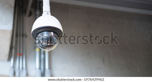 The CCTV Security camera hang on the ceiling for\
survey and protect criminal for safety people in the parking car\
building at the airport.