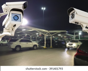 The CCTV Security Camera Operating In Parking Lot Car At Night Time Blur Background.