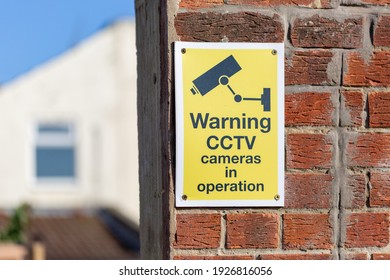 A CCTV warning sign on a brick wall outside a house
