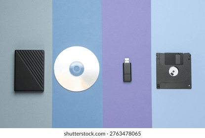 CD disk with floppy disk, USB flash drive and external hard drive on colored background. Digital information media. Flat lay