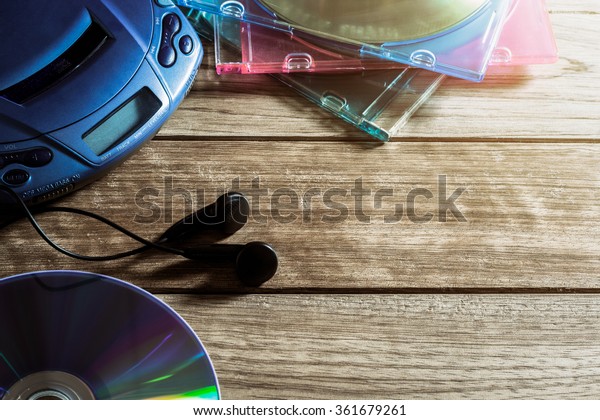 CD player with disc and earphones on wooden plank\
under warm light