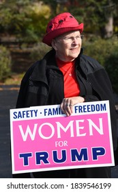 Cedarburg, WI / USA - Oct. 21, 2020: Elderly Woman Holds A Women For Trump Pink Political Sign At An Outdoor Event. She Wears A Red Hat With Republican Elephants On It. Safety, Family, Freedom Sign.