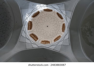 The ceiling of a building is covered in a pattern of squares and circles. The design is intricate and detailed, giving the impression of a dome. The sun is shining through the windows - Powered by Shutterstock