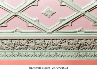Ceiling design elements. Light green gypsum bas-relief over pink background, close up. Classic architecture template