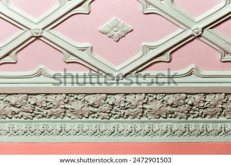 Ceiling design elements. Light green gypsum bas-relief over pink background, close up. Classic architecture template