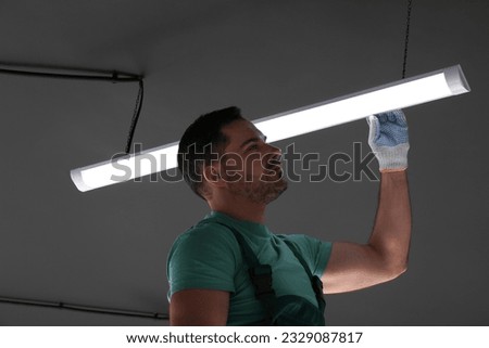 Ceiling light. Electrician installing led linear lamp indoors