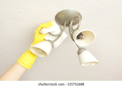 Ceiling Light Fittings With A Woman's Hand Cleaning Them With A Cloth