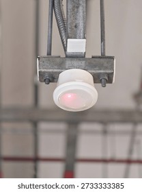 Ceiling mounted motion sensor detector installed on metal conduit, used for lighting control, security and energy efficiency in commercial building interior