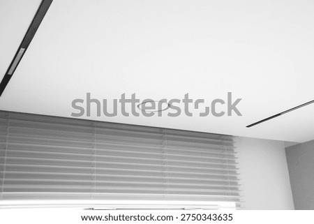 ceiling with suspended panels featuring visible track lighting, circular hidden air vents, and a window with horizontal blinds in a modern interior