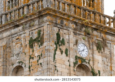 Celanova Monastery ancient stone tower showing an old clock and orange lichen growing on masonry