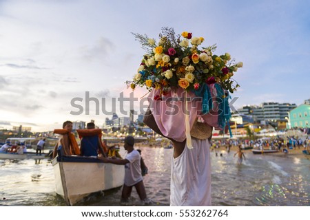 A celebrant at the Festival of Yemanja carries flowers to a boat to leave as an offering at sea on Rio Vermelho beach in Salvador, Brazil