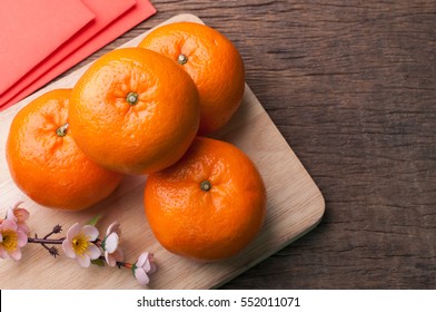 Celebrate Chinese New Year Background With Orange Fruit For Warship, Red Envelope And Beautiful Blossom.