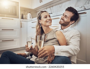 Celebrate, love and couple with champagne in kitchen for honeymoon, anniversary and valentines day. Happy, relax and young man and woman drinking alcohol on the floor with conversation in marriage