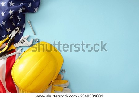 Celebrate the vital role of construction workers on American Labor Day. Top view photo of work helmet, USA flag, safety gloves, building tools on light blue background with empty space for ad or text