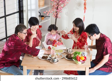 Celebrating Chinese New Year, Reunion Dinner. Asian Multi Generation Family With Red Cheongsam Dining At Home.