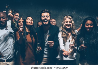 Celebrating with fun. Group of cheerful young people carrying sparklers and champagne flutes - Shutterstock ID 499219099