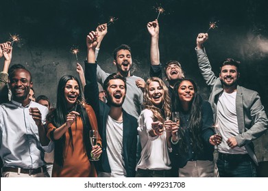 Celebrating with fun. Group of cheerful young people carrying sparklers and champagne flutes - Shutterstock ID 499231708