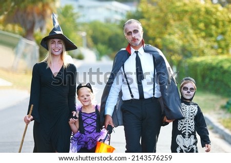 Celebrating the fun together. A cute family dressed up for Halloween walking down their street.