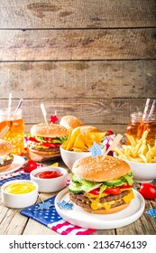 Celebrating Independence Day, July 4. Traditional American Memorial Day Patriotic Picnic With Burgers,  French Fries And Snacks, Summer USA Picnic And Bbq Concept, Old Wooden Background 