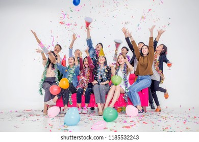 Celebrating New Year Together.Group Of Young People In Hats Throwing Colorful Confetti And Looking Happy At Office.