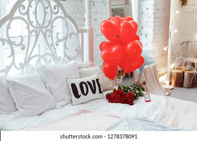 Celebrating Saint Valentine's Day with red roses on bed and air balloons in shape of heart on the bed. Gift for girlfriend on Valentine`s day,Women`s day.