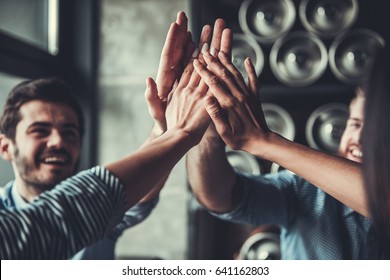 Celebrating success. Cropped image of handsome young business people celebrating success and making high five gesture in pub.