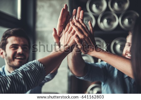 Celebrating success. Cropped image of handsome young business people celebrating success and making high five gesture in pub.