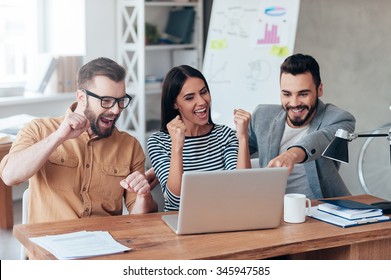 Celebrating Success. Three Happy Business People In Smart Casual Wear Looking At The Laptop And Gesturing 