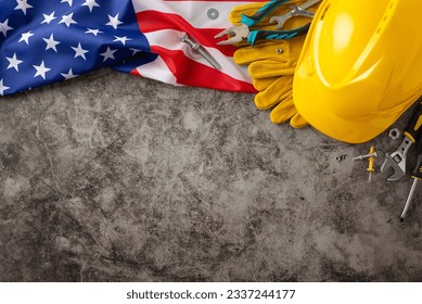 Celebrating the tireless efforts of construction workers on Labor Day. Top-down image showcasing flag, helmet, gloves, and tools on grunge textured grey concrete. Copyspace available for ads or text - Powered by Shutterstock