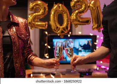 Celebrating Virtual Christmas New Year's Eve party 2021 at home during Covid-19 pandemic. Couple holding and toasting champagne glasses How to celebrate and decorate foiled balloons of 2021. 