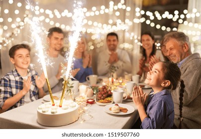 Celebration, Birthday And People Concept - Happy Family Having Dinner Party With Fountain Fireworks Or Sparkler Candles Burning On Cake At Home