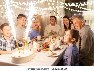 Celebration, Birthday And People Concept - Happy Family Having Dinner Party With Fountain Fireworks Or Sparkler Candles Burning On Cake At Home