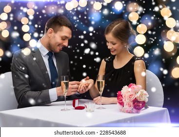 celebration, christmas, holidays and people concept - smiling couple with red gift box and ring at restaurant over night lights background - Powered by Shutterstock