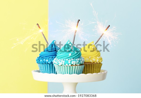Celebration cupcakes decorated with blue\
and yellow frosting and sparklers for a birthday\
party
