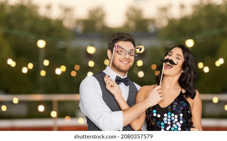 celebration, fun and holidays concept - happy couple posing with party props on roof top over lights on background - Powered by Shutterstock