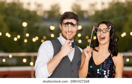 celebration, fun and holidays concept - happy couple posing with props at rooftop party over lights background - Powered by Shutterstock