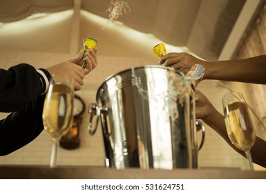 Celebration Hands Pulling A Christmas And New Year Pop Up Cracker With Champagne Glasses