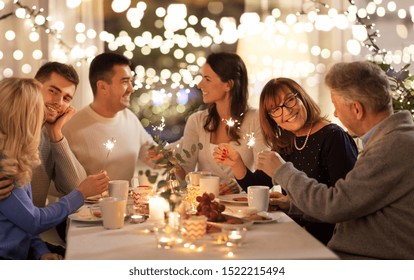 celebration, holidays and christmas concept - happy family with sparklers having fun at dinner party at home
