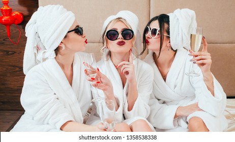 Celebration Party At Spa. Friends Congratulation. Young Women With Champagne. Sunglasses, Bathrobes And Turbans On.