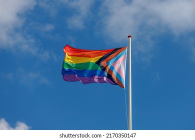 Celebration of pride month, New rainbow flag on the pole and waving in the air with blue sky as background, Symbol of Gay, Lesbian, Bisexual and Transgender, LGBT community, Worldwide social movements